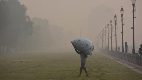 A man carriyng a huge sack near India Gate amid heavy smog conditions in New Delhi on 1 November