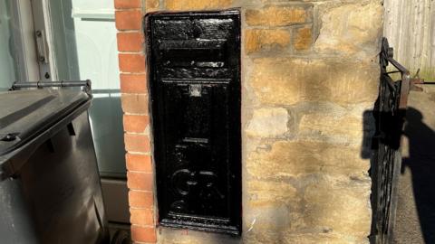 The sealed postbox painted black