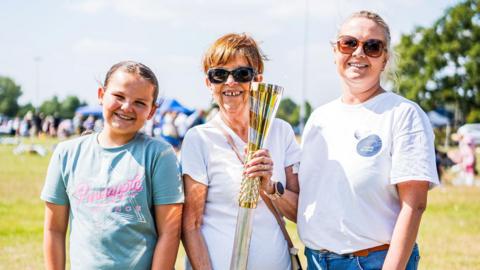 Claire Goring (right) with her mum Christine (centre) who is holding a golden baton, and daughter Ivy (left)