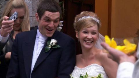 A scene from series one of Gavin & Stacey: Stacey and Gavin in their wedding attire smiling outside the church