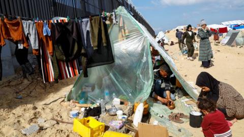 Displaced members of Palestinian Abu Mustafa family, who fled their house due to Israeli strikes, prepare food as they shelter at the border with Egypt, in Rafah in the southern Gaza Strip