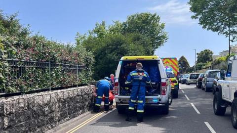 Two emergency service workers opening the back of an emergency service vehicle. 