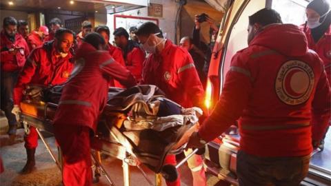 Volunteers from the Syrian Arab Red Crescent load a sick civilian into an ambulance in Douma on the third night of evacuations from the besieged rebel enclave of eastern Ghouta on the outskirts of the capital Damascus late on December 28, 2017
