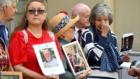 Members of the Covid-19 Bereaved Families for Justice hold photos of relatives who died during the pandemic, as they demonstrate outside the venue for the UK Covid-19 Inquiry, ahead of its first day in west London on June 13, 2023.