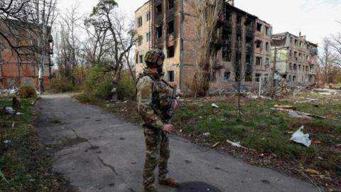 Ukrainian soldier views building in Avdiivka hit by Russian strikes