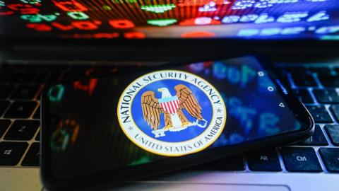 The National Security Agency logo appears on a phone on top of a laptop