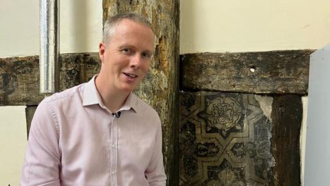 Andrew standing in front of a tudor painting