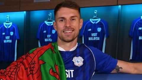 Aaron Ramsey in Cardiff kit with the Welsh flag draped over his shoulder
