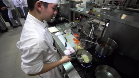 Joel Chow frying onions over gas flame on hob