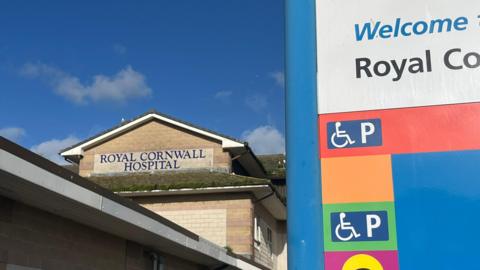 A brick building with a pitched roof and 'Royal Cornwall Hospital' in blue lettering