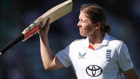 Heather Knight raises her bat as she leaves the pitch in her final innings for England