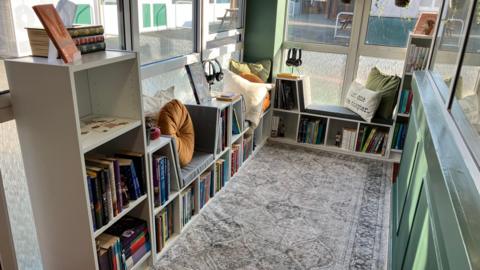 Lots of book shelves with lots of books and seats integrated into a space.