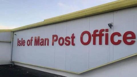 Large lettering on the side of post office headquarters that says Isle of Man Post Office in red on a shite background.