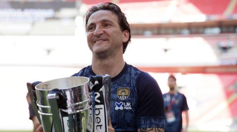Notts County boss holds the League Two play-off trophy after his side beat Salford City at Wembley