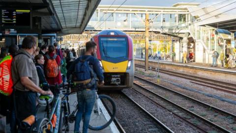 Commuters waiting on a platform to board an approaching train. 