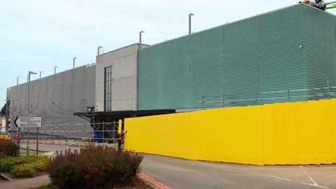 A nearly-finished car park behind bright yellow hoardings