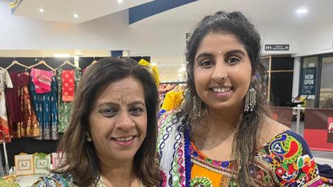 Mother and daughter Parul Chauhan (left) and Bhavini Vithlani smiling wearing vibrant sarees as they celebrate the Hindu festival of Navratri