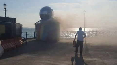 A person running towards the small fire armed with what appears to be a fire extinguisher