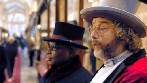 World Champion whistler Geert Chatrou whistles in Burlington Arcade wearing a red velvet suit and a grey top hat.