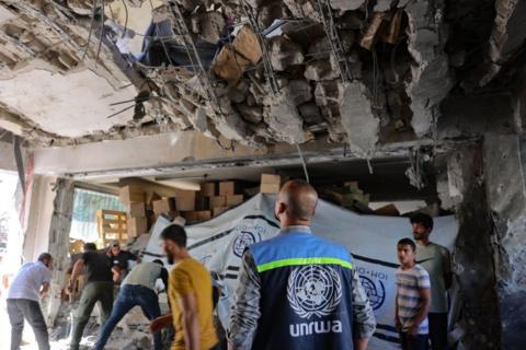 An UNRWA worker and displaced Palestinians check the damage inside a UN school-turned-refuge in Gaza City (pictured: October 19, 2024.)