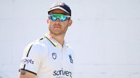 Sam Hain wearing mirrored sunglasses about to take the field for Warwickshire