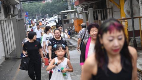 People walk in an alley behind a commercial district in Beijing.