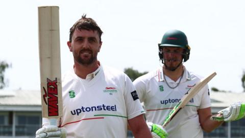 Leicestershire's Lewis Hill hold his bat up as he leaves the field