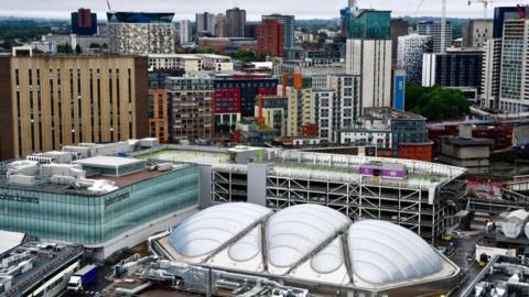 An aerial view of Birmingham city centre from the Rotunda showing the city skyline with high and low rise buildings, John Lewis and the multi-storey car park next door.