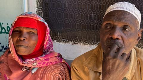 Headshots of a woman in a red head covering and a scarf on the left and a man with a white skullcap on the right biting his finger in thought. 