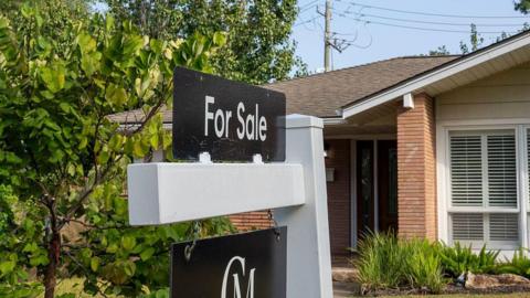 A for sale sign is seen in front of a house in a neighbourhood in Houston.