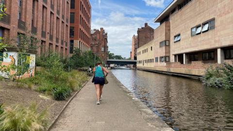 Woman in the middle distance, in running gear, beside Nottingham canal