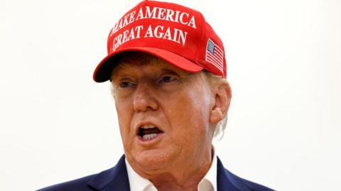 Donald Trump wears a red hat emblazoned "make America great again"