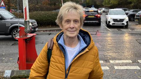 Older woman in coat standing on road