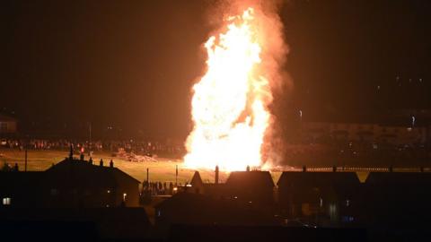The Craigyhill housing estate on July 12 in Larne, County Antrim, showing fire rising up from the bonfire against a black background