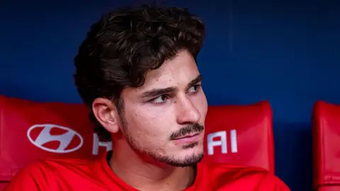 Julian Alvarez pictured looking to the side while sat on the bench during Atletico Madrid's match against Villarreal in August.
