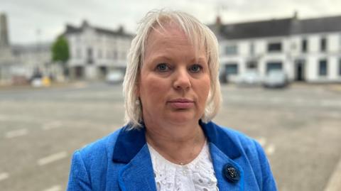 Shows Michelle Knight-McQuillan in a blue jacket and white top 