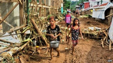 Children walking past destroyed houses