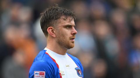 Football Archie Davies wearing a blue, white, and red Carlisle United shirt during an EFL football match.