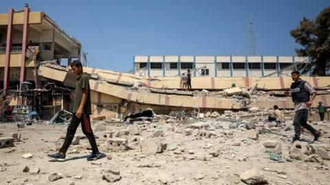 Palestinians inspect damage following an Israeli strike on Mustafa Hafez school, which was sheltering displaced people, in Gaza City, in the northern Gaza Strip (20 August 2024)