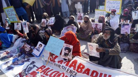 Protesters hold photos of their missing relatives in Dera Ismail Khan