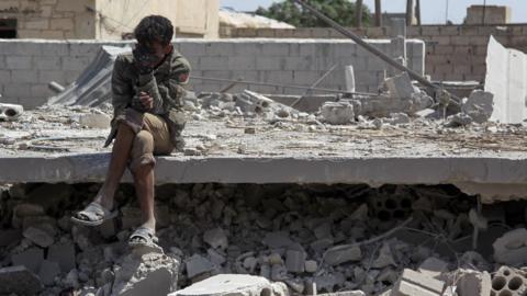 A Syrian man sits amid the rubble of a building destroyed in a reported government air strike in Saraqeb, Idlib province (7 May 2019)