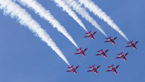 The Red Arrows take fly in a sequence with a trail of smoke behind them