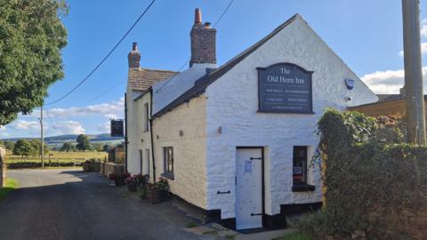 The exterior of the Old Horn Inn pub, which is painted white.