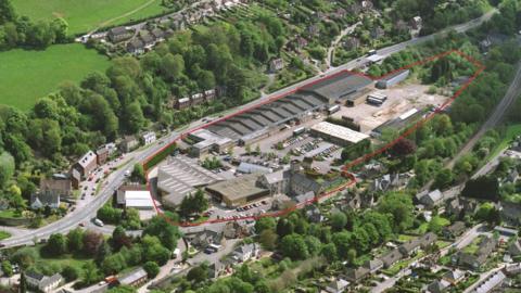 An aerial shot of the site of the Brimscombe Port development in Stroud, which has a red ring drawn around it. It is in a valley with a main road to one side and is surrounded by trees and houses.