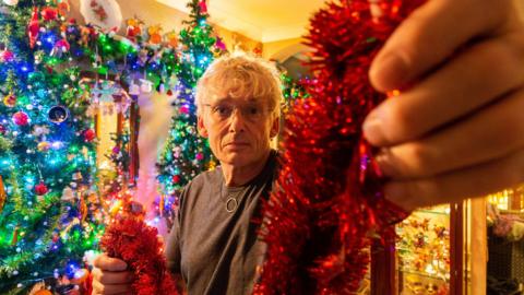 A man holds Christmas decorations. 