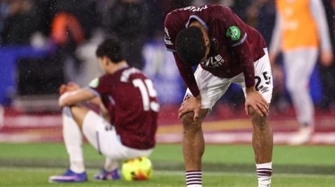 Image showing a West Ham player leaning over with hands on knees while another sits on a ball in the background