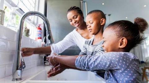 Stock photo of family washing hands in the kitchen sink