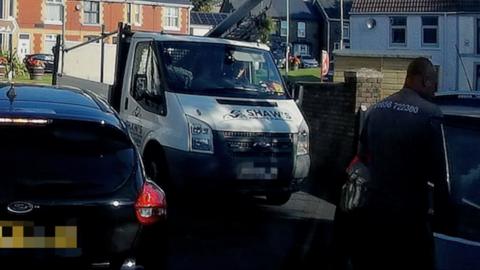 A van and a man looking in the window of a car