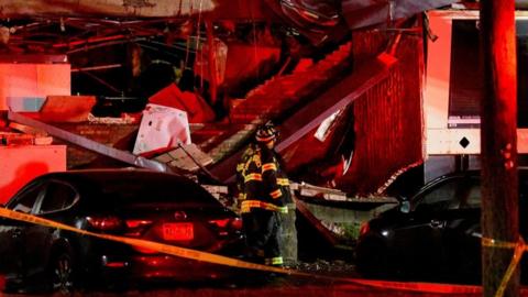 A fire worker stands by the mangled ruins of an exploded building