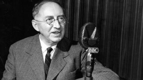 Black and white image of EM Forster facing towards a microphone with a '鶹Լ' logo on it.